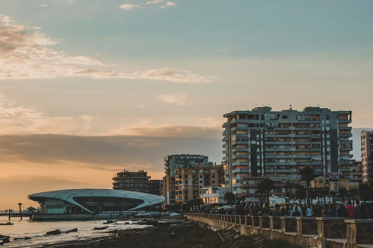 Le front de mer de Durrës en fin de journée : la promenade, les immeubles et la jetée dans une lumière dorée