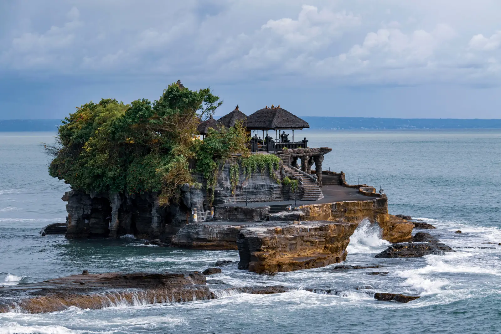 Le temple de Tanah Lot perché sur son îlot rocheux couvert d’arbres, battu par les vagues